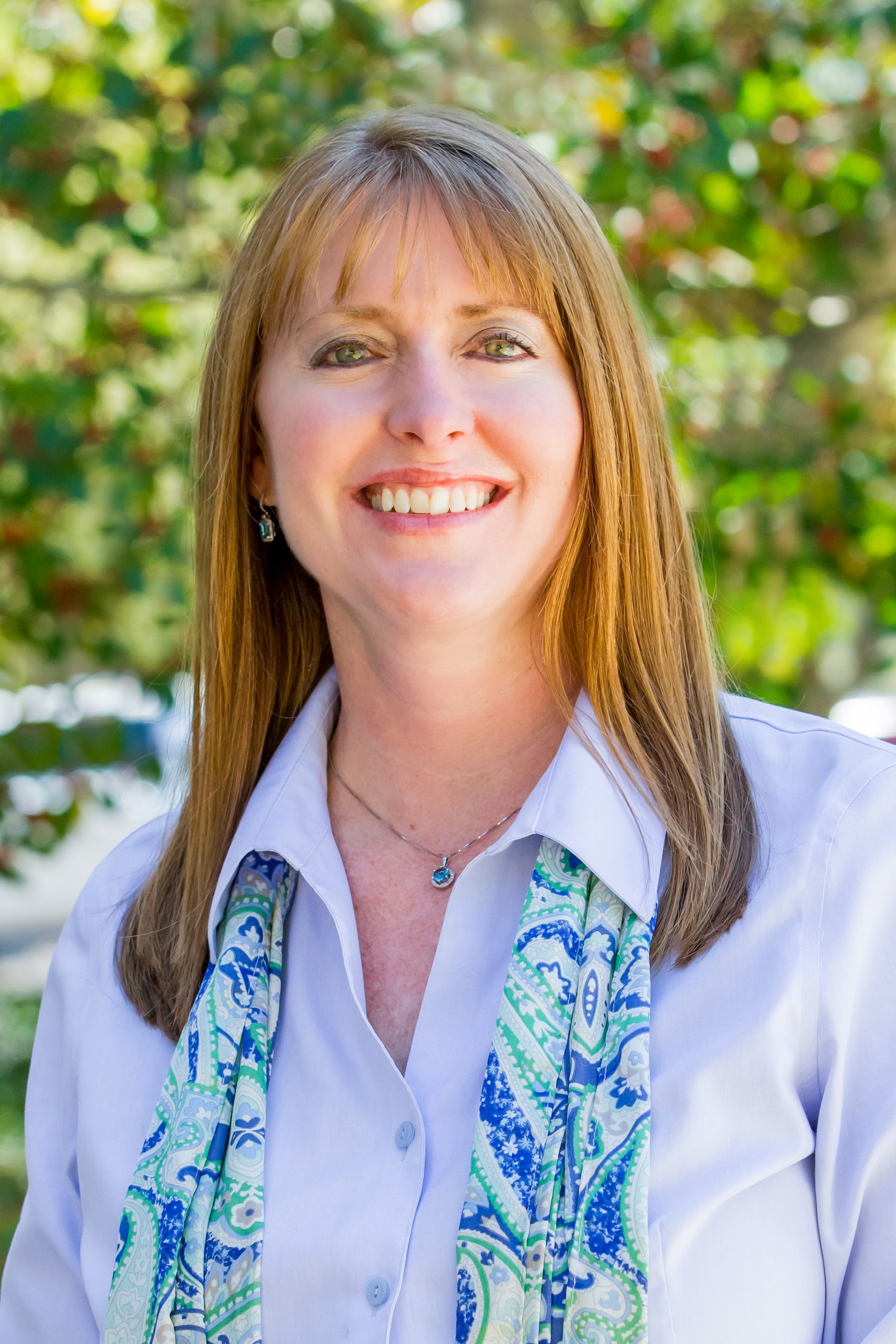 A woman with long hair wearing a white shirt and blue tie.