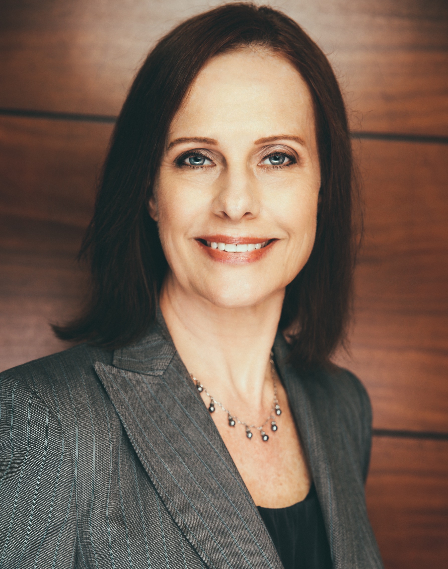 A woman with long hair wearing a gray suit.