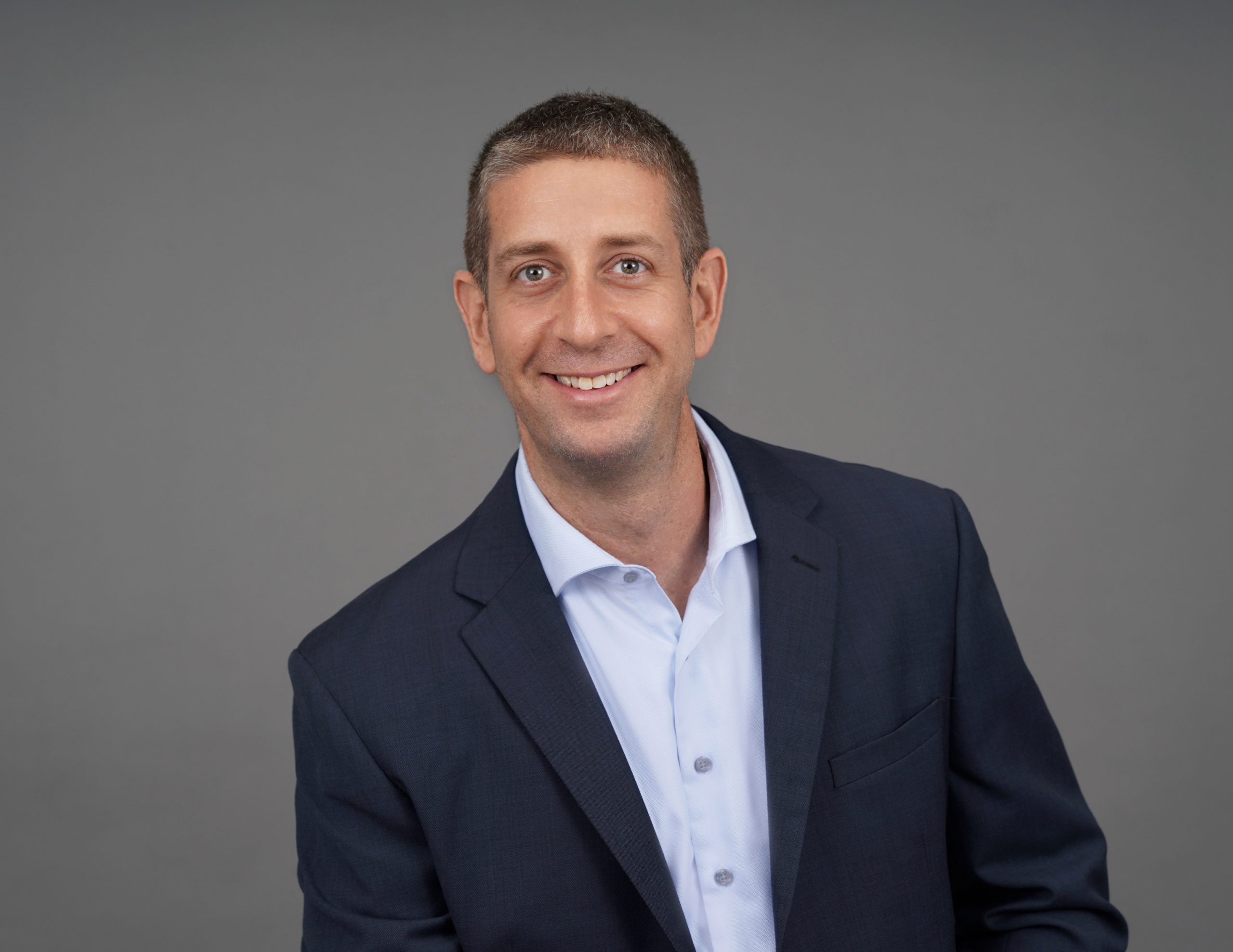 A man in a suit and tie smiling for the camera.